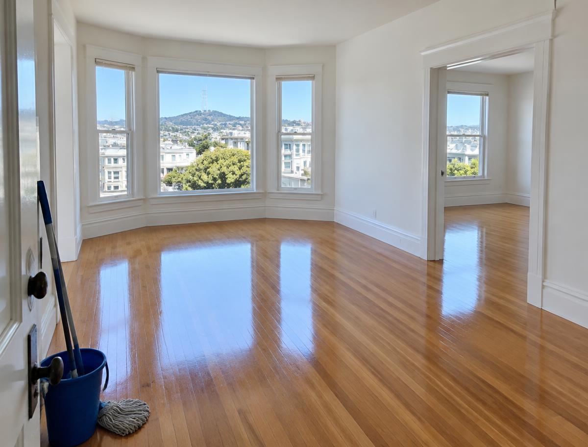 Empty apartment with shining hardwood floors and a mop and bucket by the door